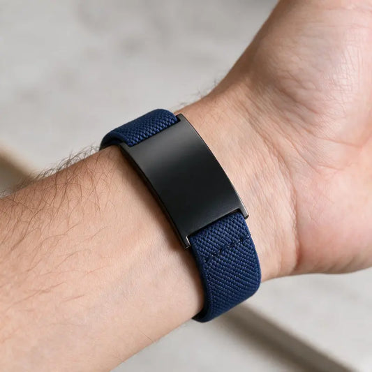 Pulse navy elastic band bracelet with black ID plate, worn on a man's wrist.