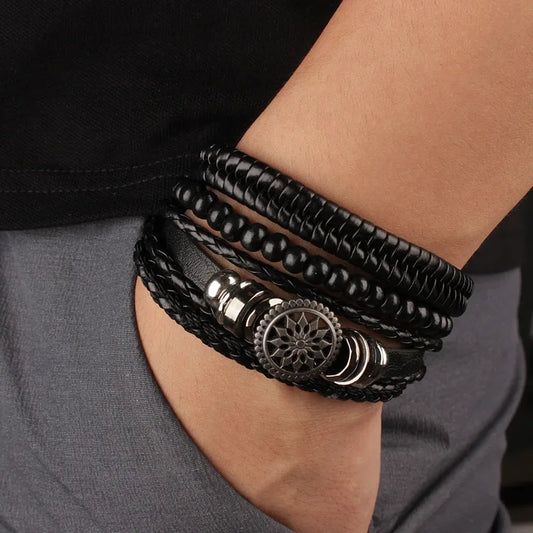 Black leather layered bracelet stack with a mandala charm worn on the wrist, paired with dark clothing.