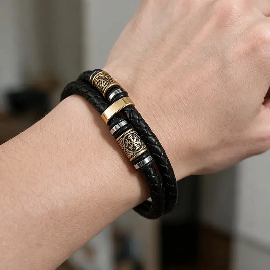 Black double-strand leather bracelet with an antique bronze Norse rune charm bead, worn on a man's wrist.