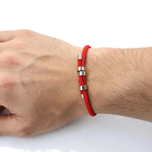 Red nylon cord bracelet with stainless steel end caps and a sliding knot closure, worn on wrist