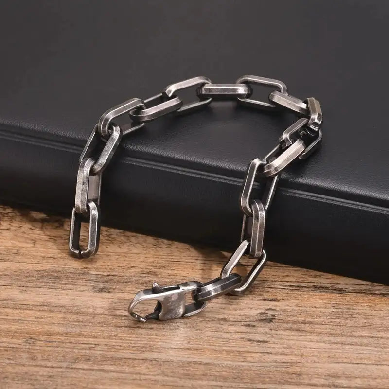 Close-up of an oxidized paperclip chain bracelet resting on a wooden surface