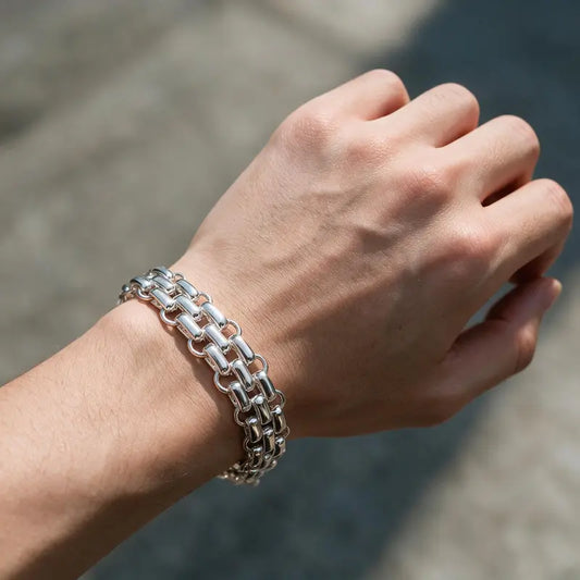 Chunky silver woven box-link chain bracelet with round tag worn on the wrist