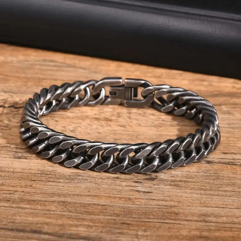Close-up of a heavy 12mm oxidized Cuban link bracelet resting on a wooden surface