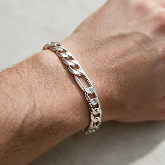 Silver flat figaro chain bracelet worn on the wrist