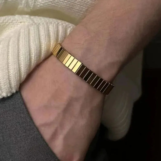 Close-up of a wrist wearing the gold stretch bracelet, person dressed in a cream knit sweater