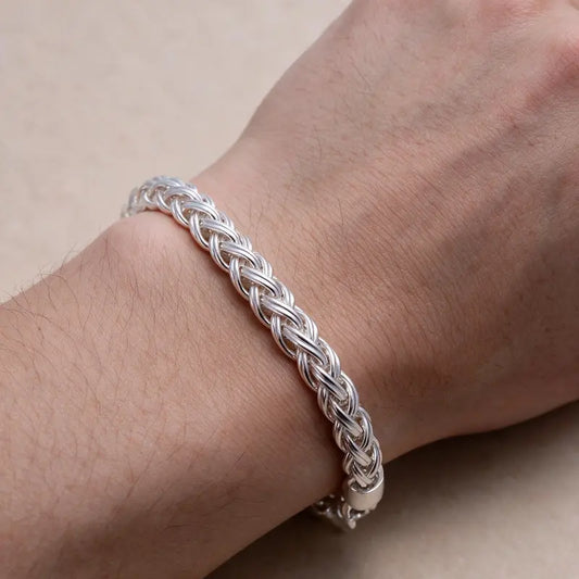 Silver wheat-chain bracelet worn on a man's wrist, close-up.