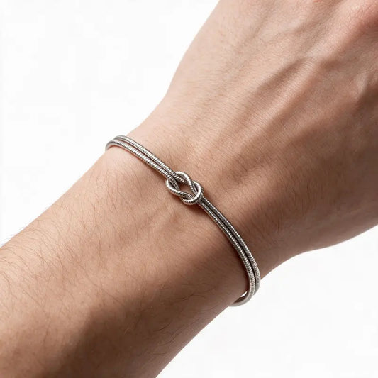 Silver stainless steel knot chain bracelet worn on wrist, white background