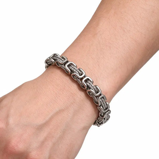 Silver stainless steel byzantine link bracelet worn on wrist, white background