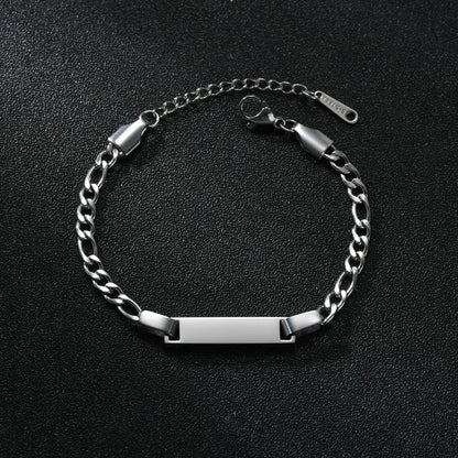 Silver curb-chain bracelet with a plain rectangular nameplate, smaller kids-sized scale, on a black textured background.