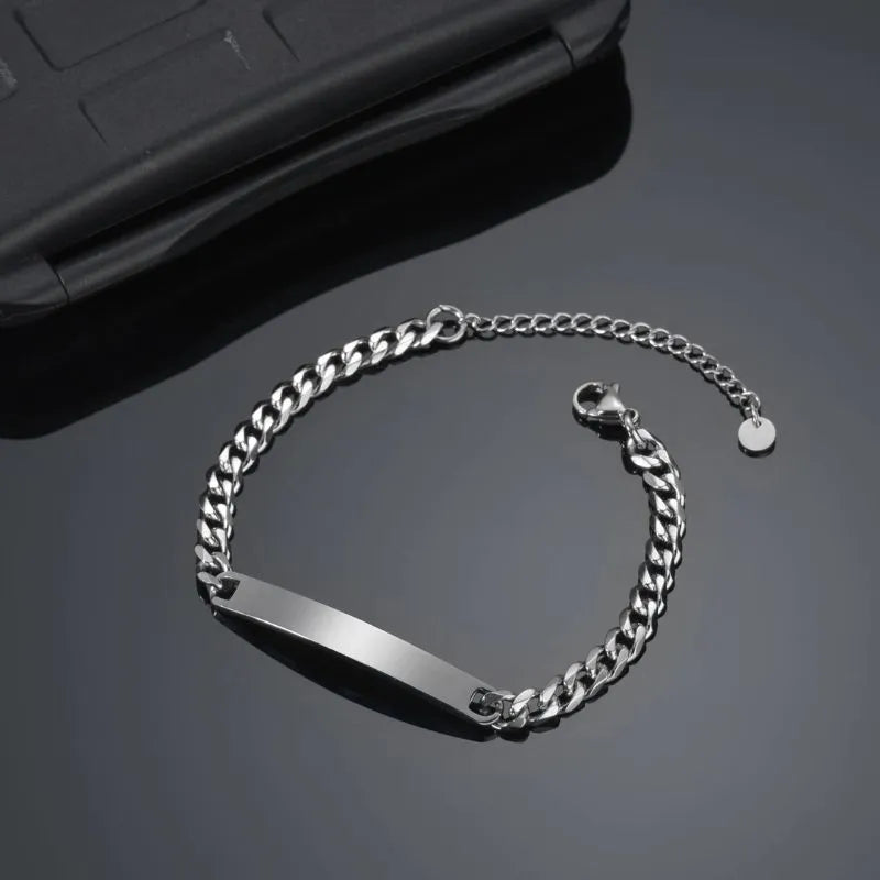 Blank silver nameplate bracelet resting beside a phone case