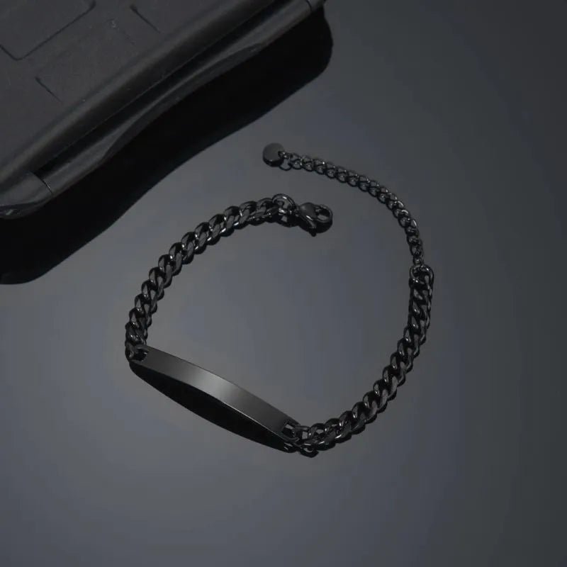 Blank black nameplate bracelet resting beside a phone case
