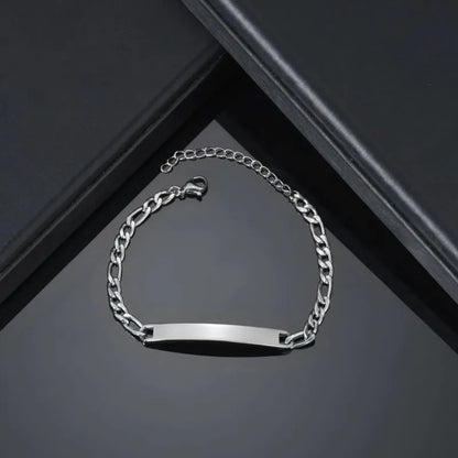 Blank silver figaro-link nameplate bracelet displayed on an angular black gift box