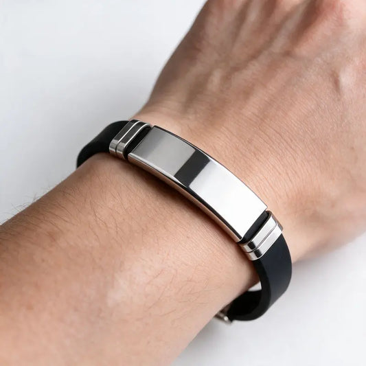 Onyx black silicone bracelet with silver ID plate, worn on a man's wrist.