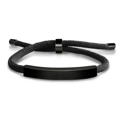 Black woven cord bracelet with a black-finish nameplate and matching black adjustable slider clasp, on a white background.