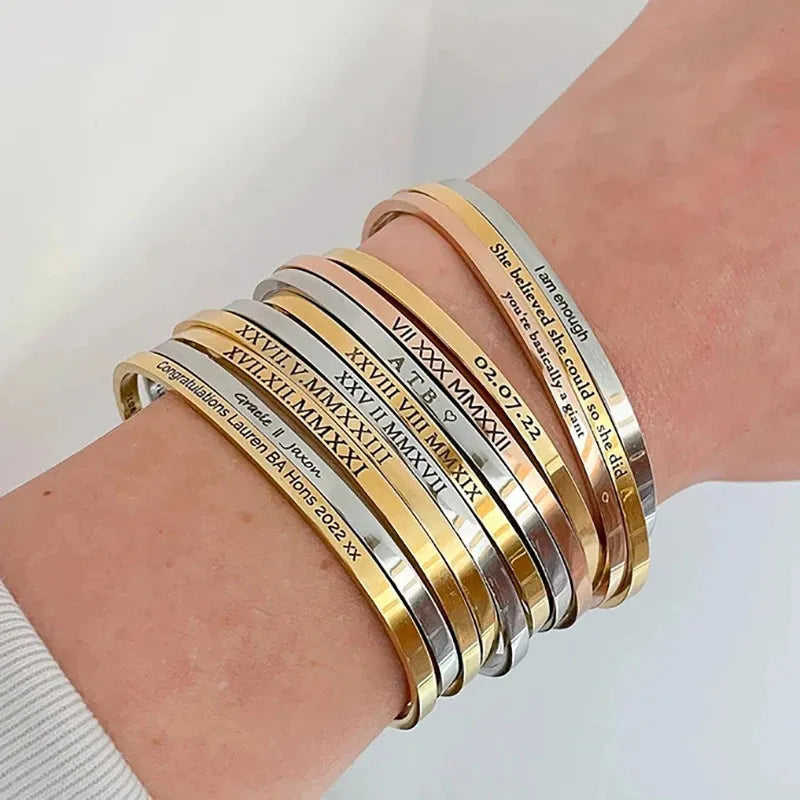 Multiple Customised Men's Bracelet – Whisper Cuff Bangles stacked on a wrist in Gold, Silver and Rose Gold with various engravings.