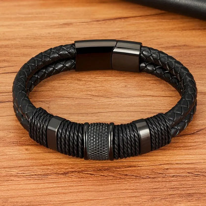 Black woven leather rope bracelet with stainless steel accents, angled view on a wood background