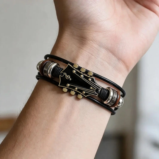 Black leather bracelet with a black enamel guitar-headstock charm and wood bead spacers, worn on a man's wrist.