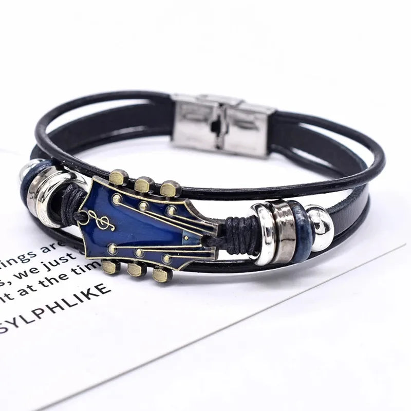 Black leather bracelet with a blue enamel guitar headstock charm, on a white background