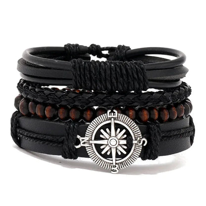Black leather layered bracelet stack with a silver compass charm and brown wood beads, on a white background.