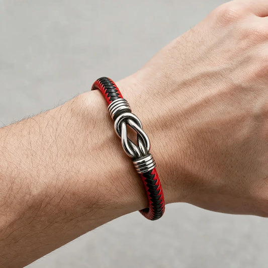 Black leather bracelet with a silver infinity-knot centerpiece clasp, worn on a man's wrist.