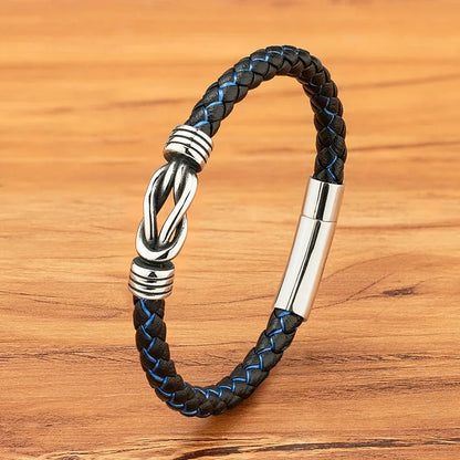Black and blue braided leather bracelet with a polished stainless steel infinity-knot clasp, on a wood background