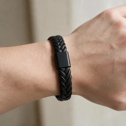 Black herringbone-woven leather bracelet with a matte black magnetic clasp, worn on a man's wrist.