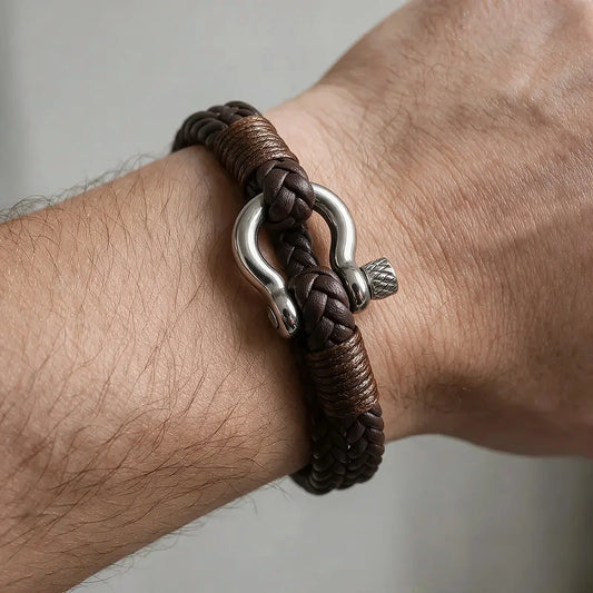 Brown braided leather bracelet with a silver shackle-style clasp, worn on a man's wrist.