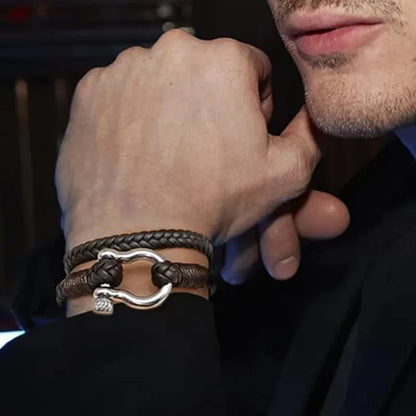 Man wearing a black braided leather bracelet with a stainless steel shackle clasp on his wrist