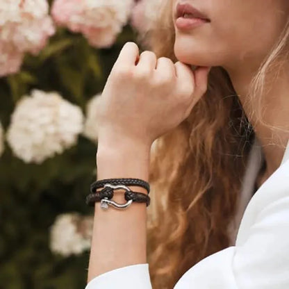 Woman wearing a black braided leather bracelet with a stainless steel shackle clasp on her wrist