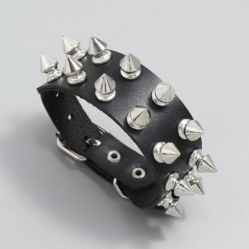 Angled view of a black leather cuff bracelet with three rows of silver spike studs