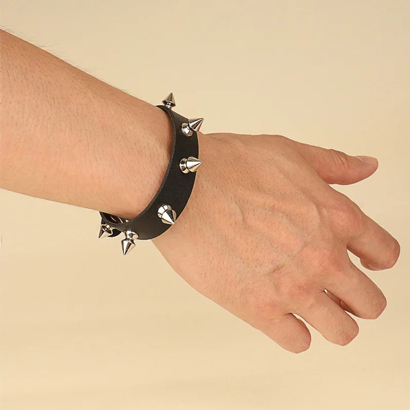 Black leather cuff bracelet with a single row of spike studs worn on the wrist