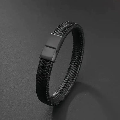 Black braided leather bracelet shown at an angle on a dark textured surface.