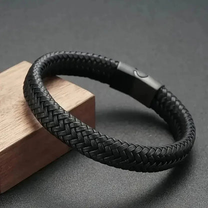 Black braided leather bracelet draped over a wooden block on a dark surface.