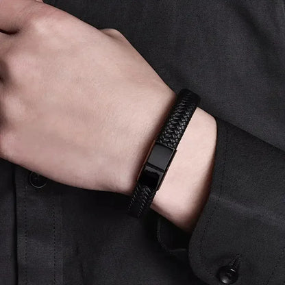 Black braided leather bracelet worn on the wrist, paired with a black jacket cuff.