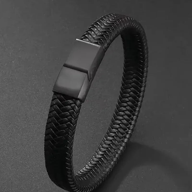 Black braided leather bracelet shown at an angle on a dark textured surface, clasp facing up.
