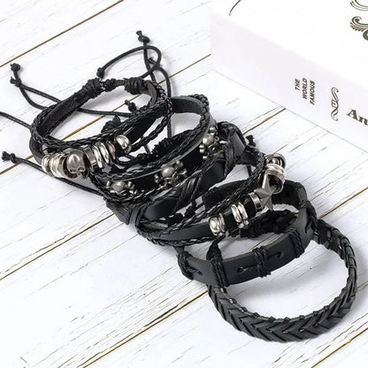 Six-piece black leather bracelet stack laid on a wooden surface next to a white gift box, with adjustable drawstring ends visible.