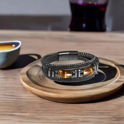 Black leather tiger eye bracelet displayed on a wooden tray on a café table
