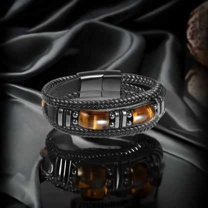 Black leather tiger eye bracelet on a dark satin background with dramatic lighting