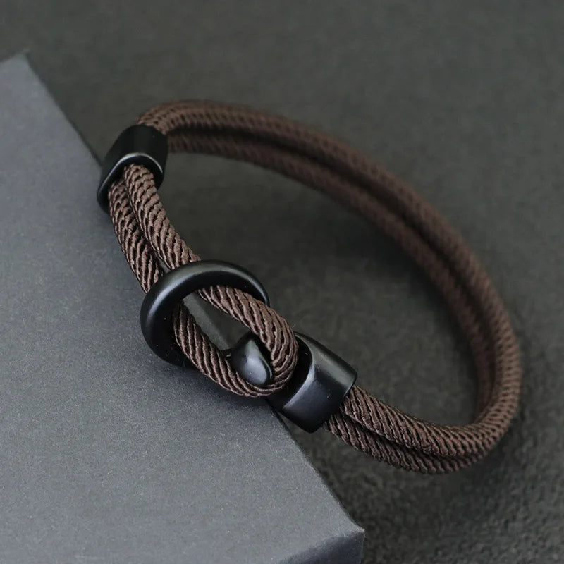 Close-up of the black alloy hook clasp on a brown double-wrap rope bracelet