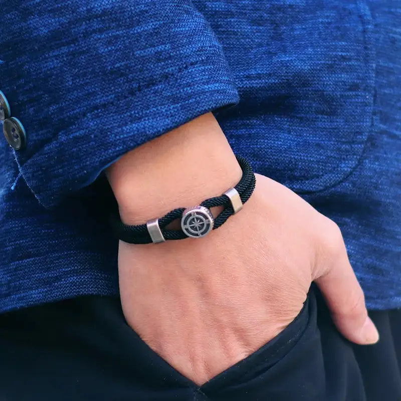 Black compass charm rope bracelet worn on the wrist