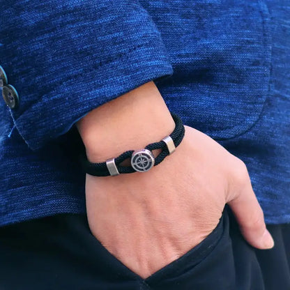 Black compass charm rope bracelet worn on the wrist