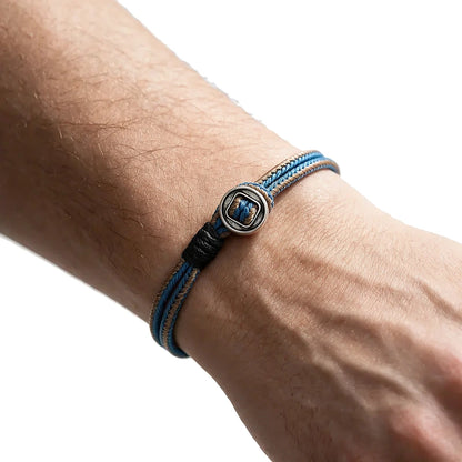 Blue and black two-tone woven cord bracelet with a silver toggle bead, worn on wrist
