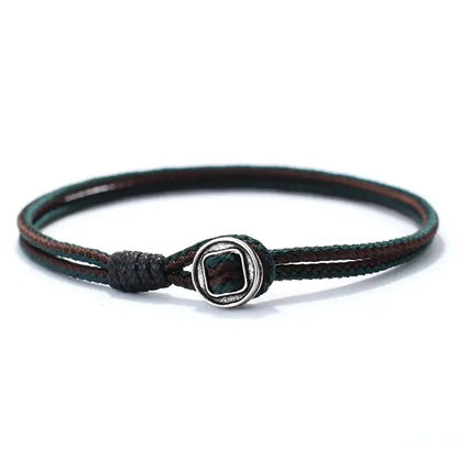 Green and black two-tone woven cord bracelet with a silver toggle bead