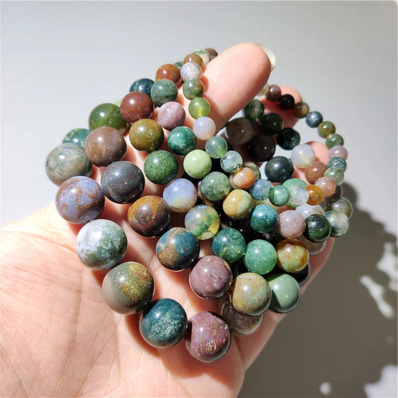 Multiple Indian agate bead bracelets held in hand, close-up detail