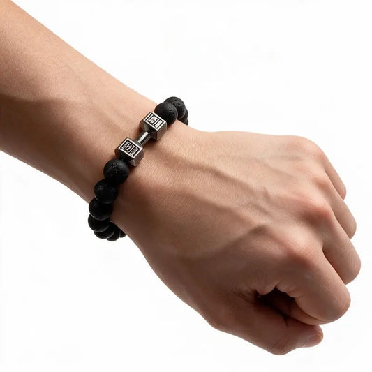 Black lava stone bead bracelet with black dumbbell charm worn on wrist, white background
