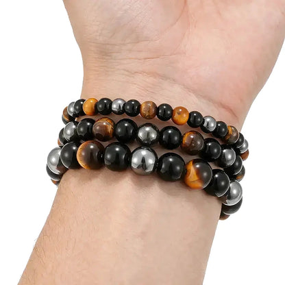 Three stacked bead bracelets combining tiger eye, black obsidian, and hematite beads, worn on a man's wrist.