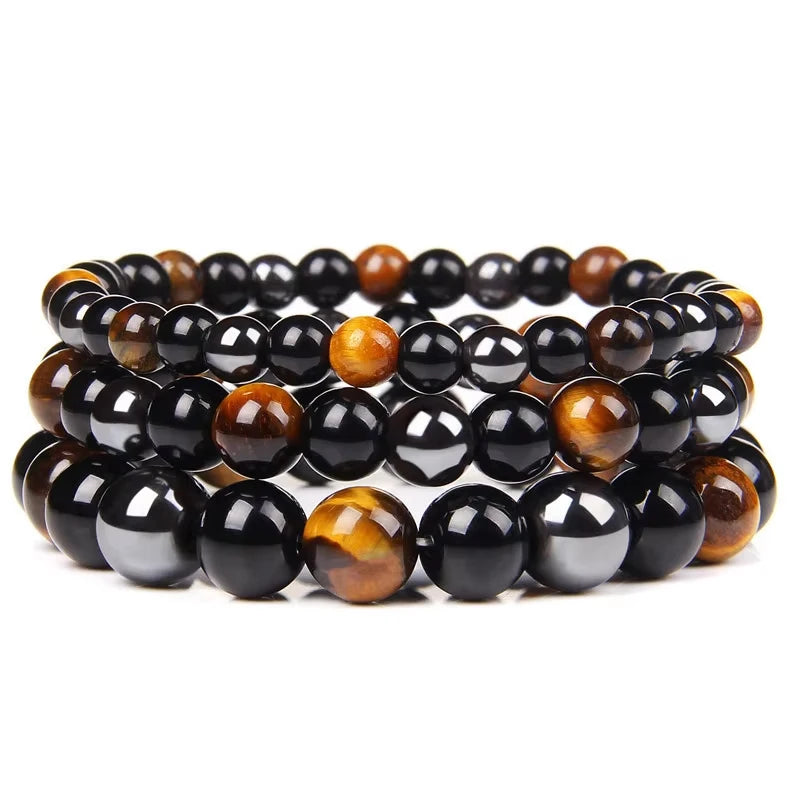 Triad Protection bracelets layered on a tray, tiger eye and black obsidian beads