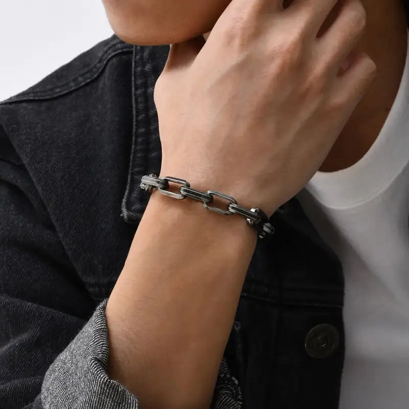 Man wearing an oxidized paperclip chain bracelet on his wrist with a denim jacket
