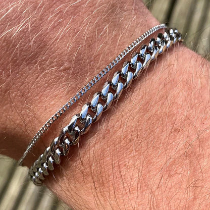Thin and thick silver Cuban link chain bracelets stacked and worn on the wrist