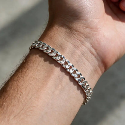 Silver diamond-cut flat curb chain bracelet worn on the wrist